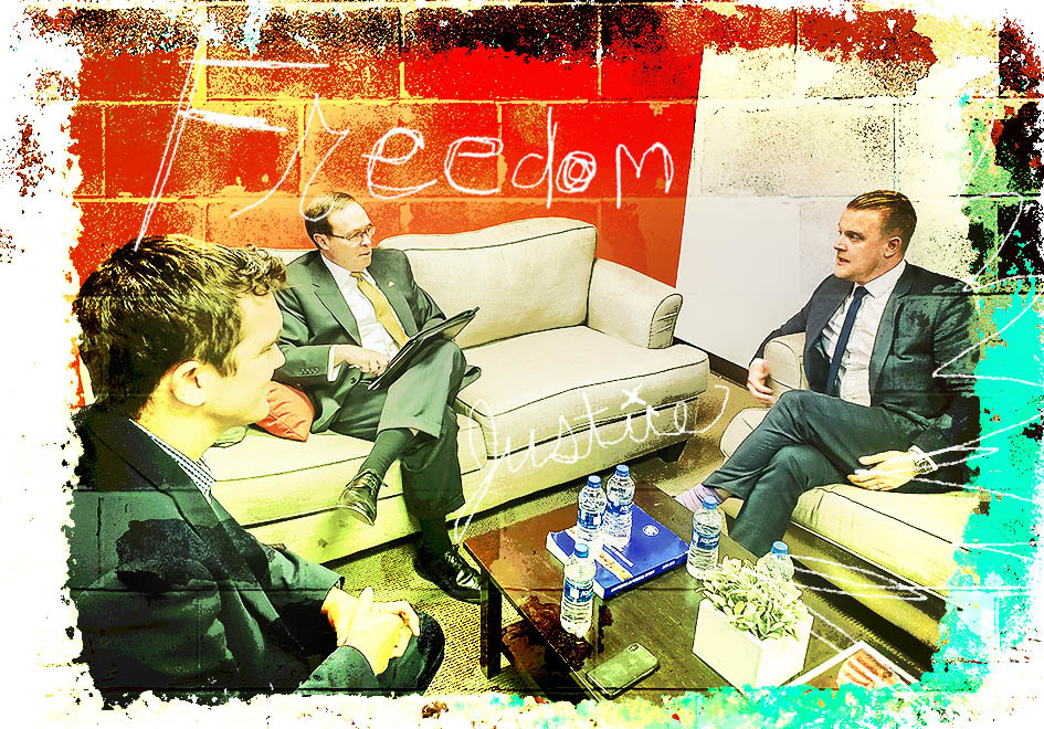 three businessmen seated and speaking to each other