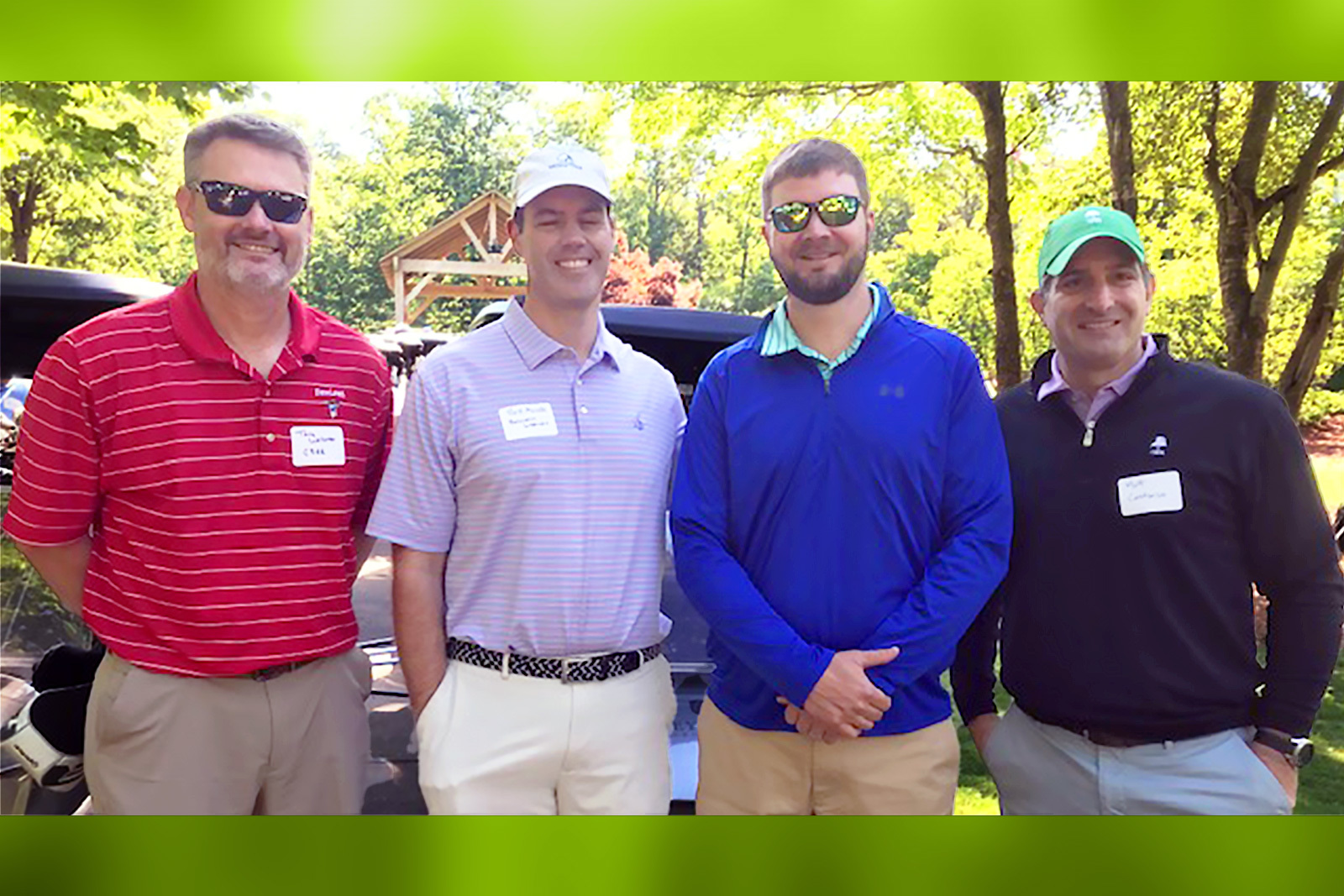 four men standing together and smiling at camera