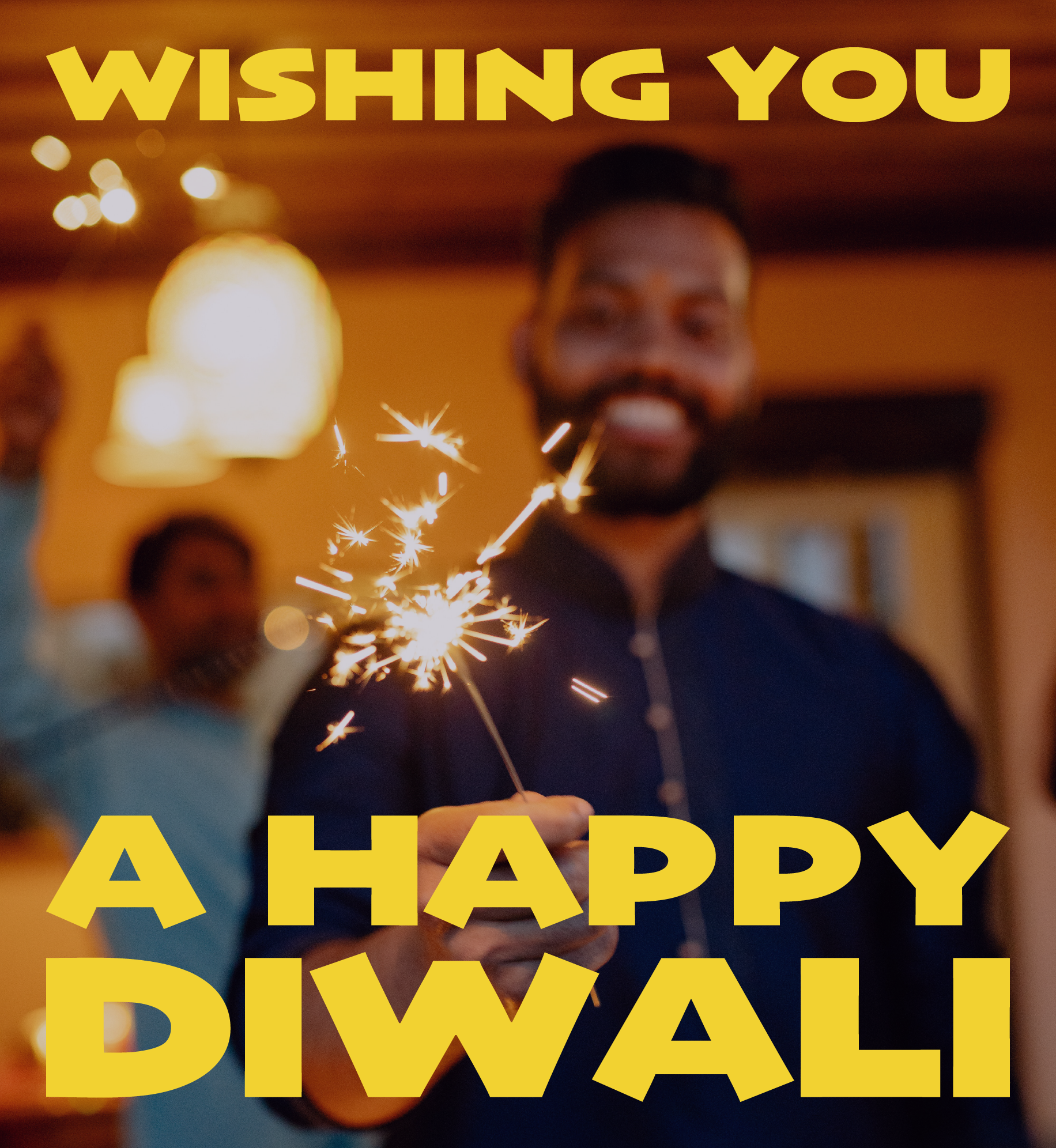 Man smiling and holding sparkler. Text: Wishing you a Happy Diwali.