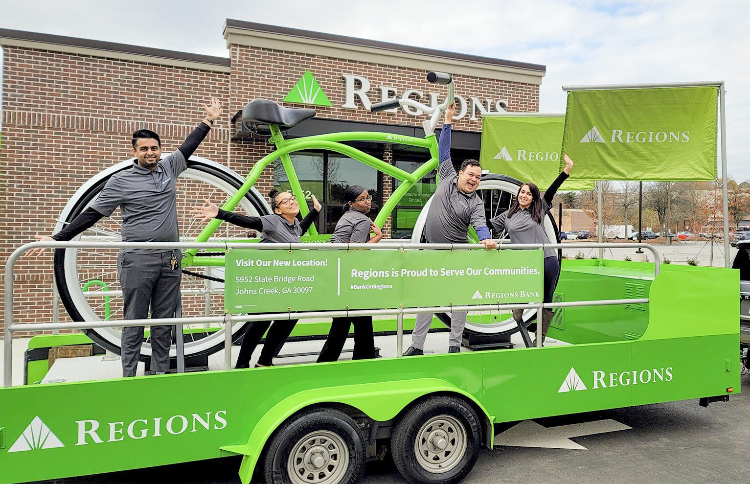 Regions Bank associates in front of big green bike.