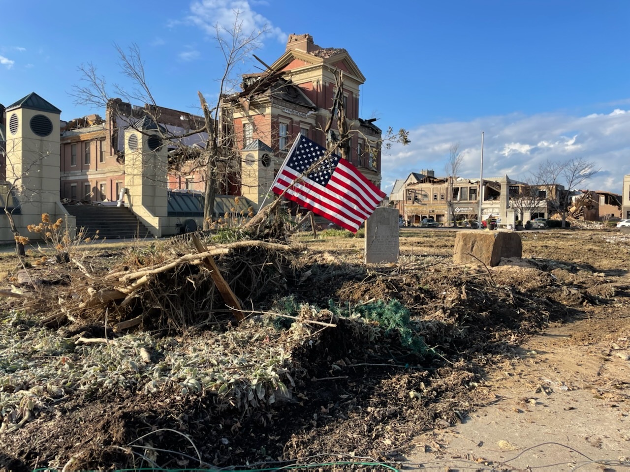 photo of damage around mayfield courthouse with American flag in the center of the frame