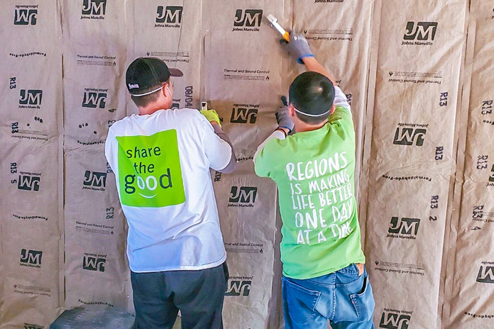 Lee H and Po N. installing insulation while wearing "Share the Good" shirts.