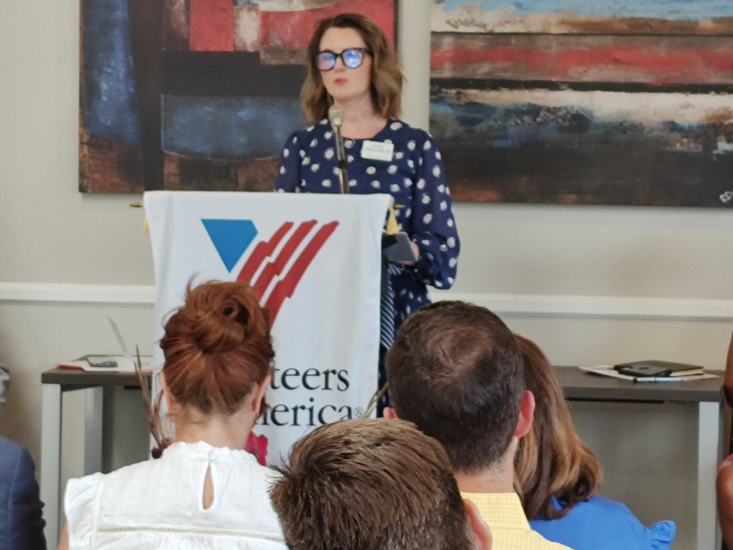 a woman is at a podium in front of a crowd. 