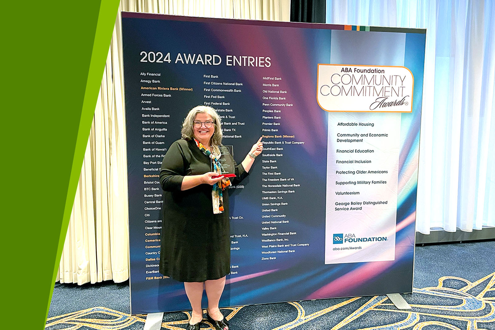 Person holding an award and smiling, pointing to Regions Bank...