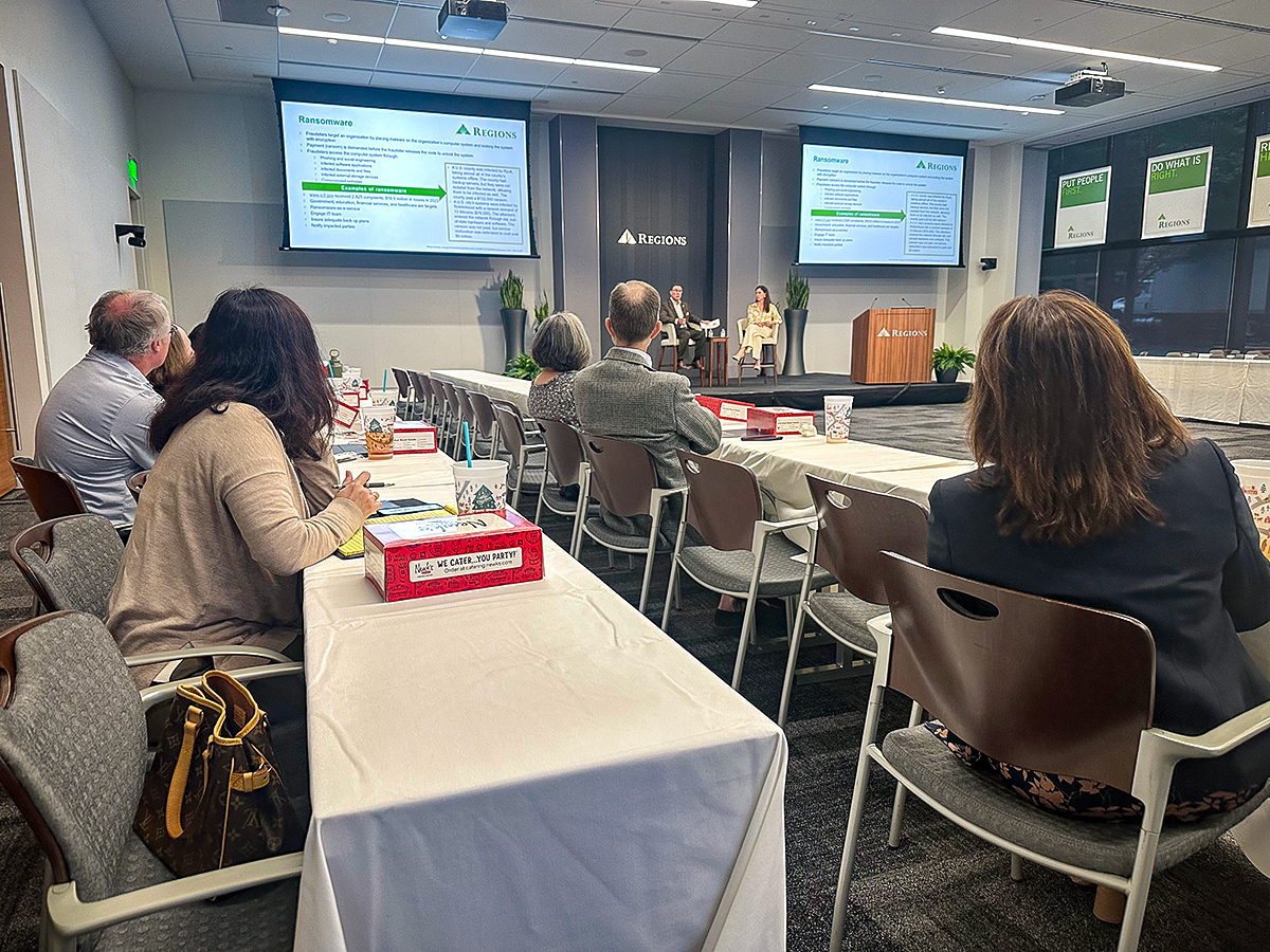 Group of Regions associates sitting at tables in the audience listening and watching two presenters on stage.