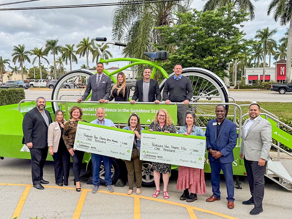 Miami Celebration Week, group of people holding two Regions checks and standing in front of the big bike.
