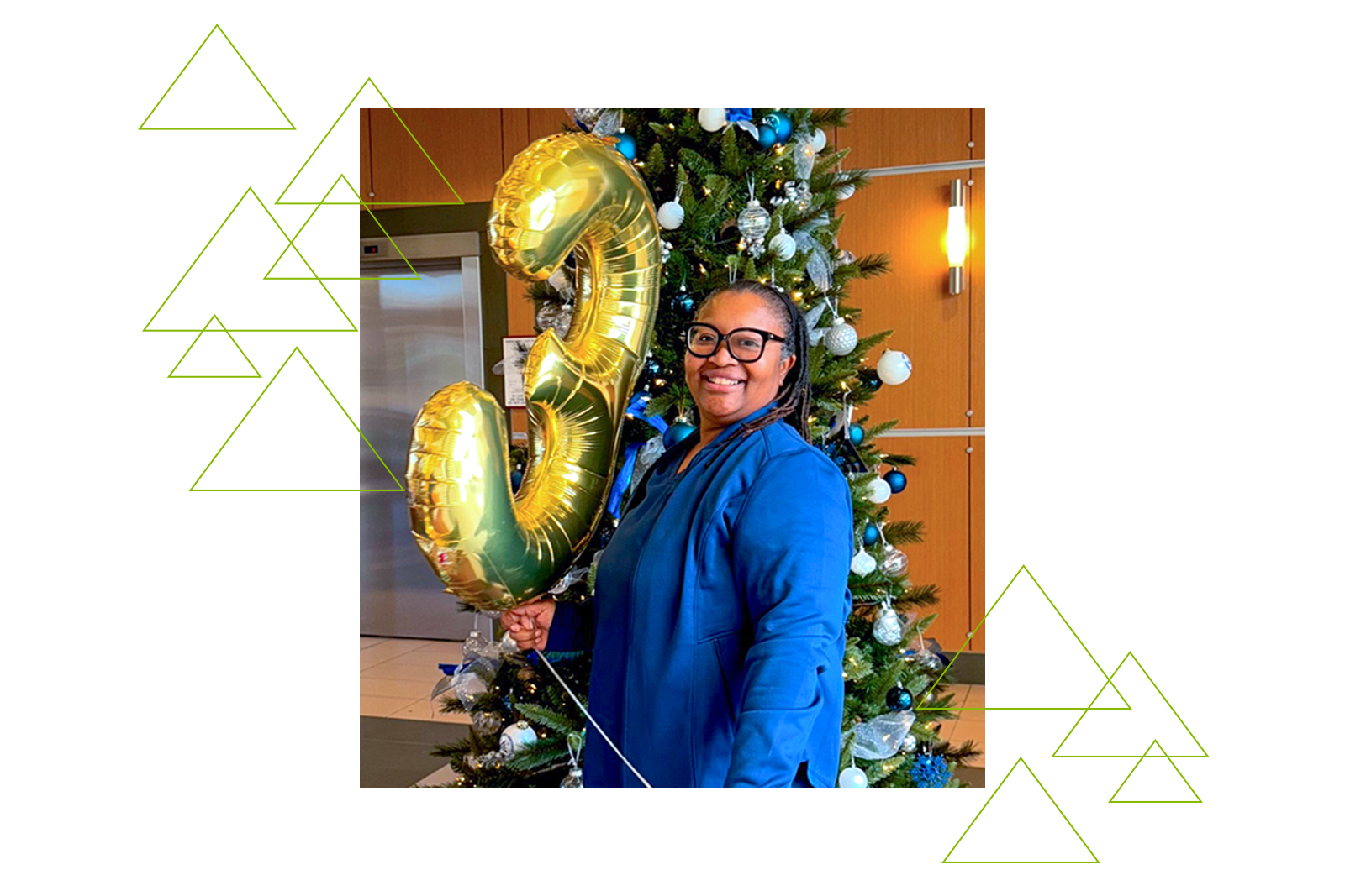 Andrea Davis-Lloyd standing in front of a Christmas tree with a number three balloon.