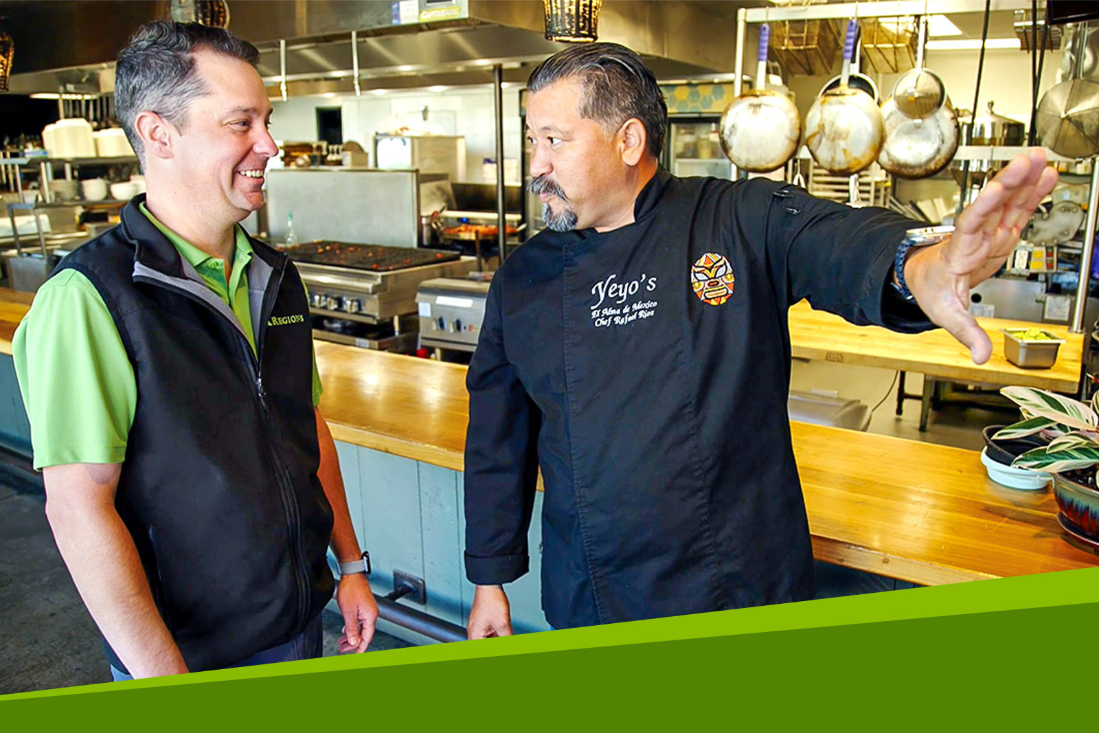 Two people standing in front of an open commercial kitchen...