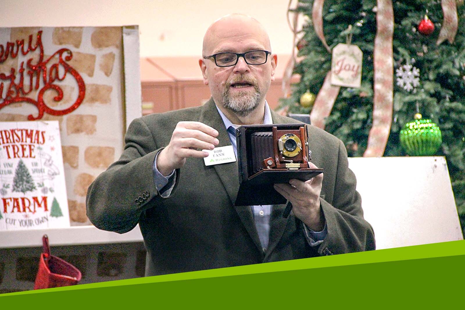 Rob Fann presenting an antique camera at an event. 
