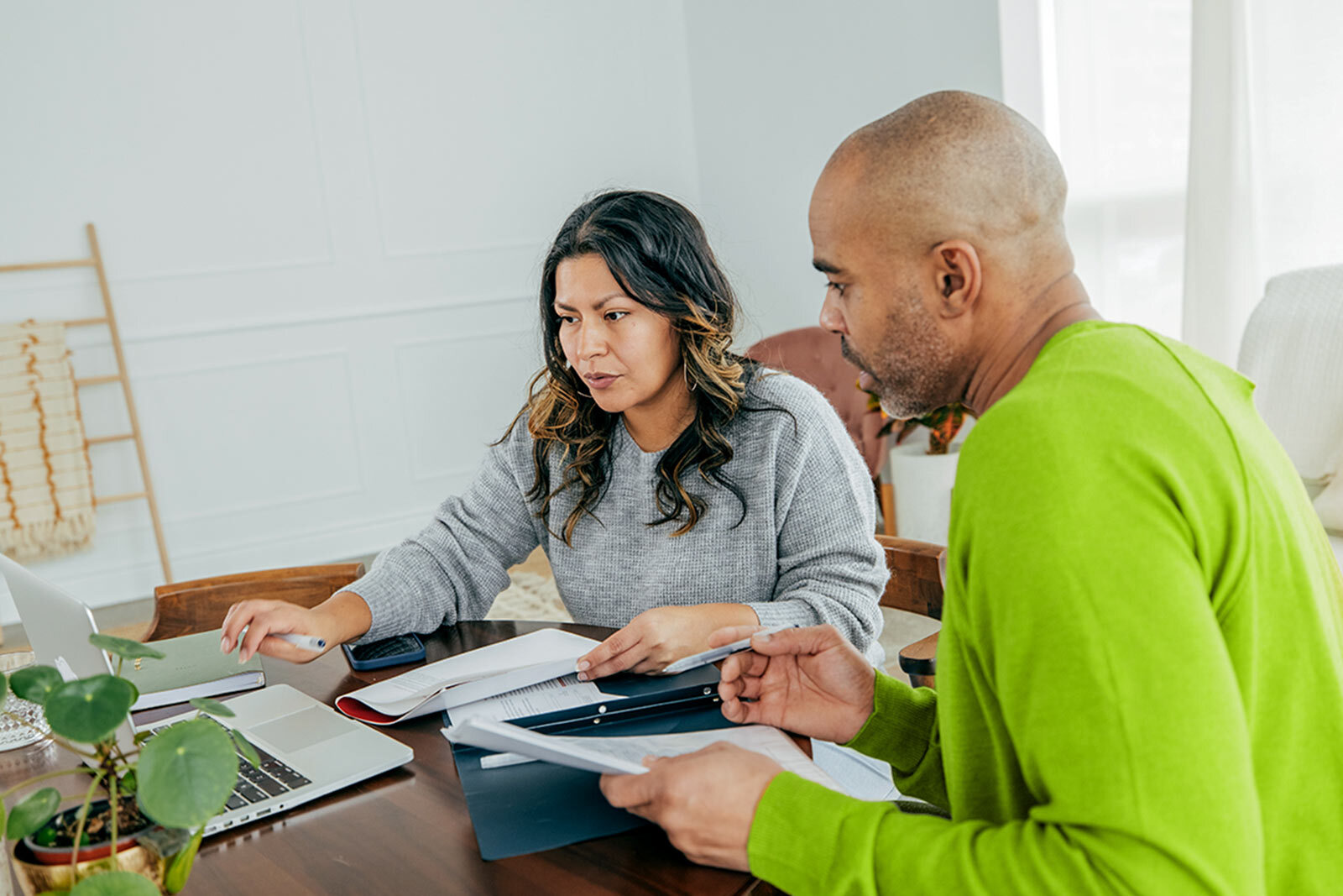 A young couple sitting at a table with a computer, preparing their taxes ahead of the April 15th tax deadline.