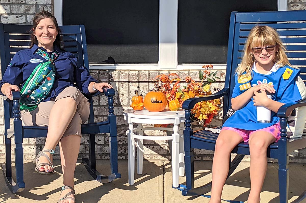 Jessica Saylor, project manager with Regions Bank’s Branch Analytics and Strategy team and Girl Scout leader and her daughter, Genevieve Saylor, a Junior Girl Scout sitting on a porch.