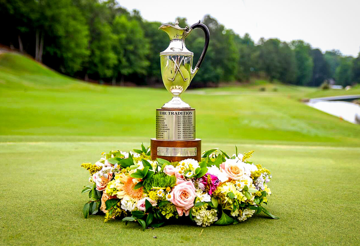 Regions tradition trophy sitting on a golf course surrounded by flowers at the base.