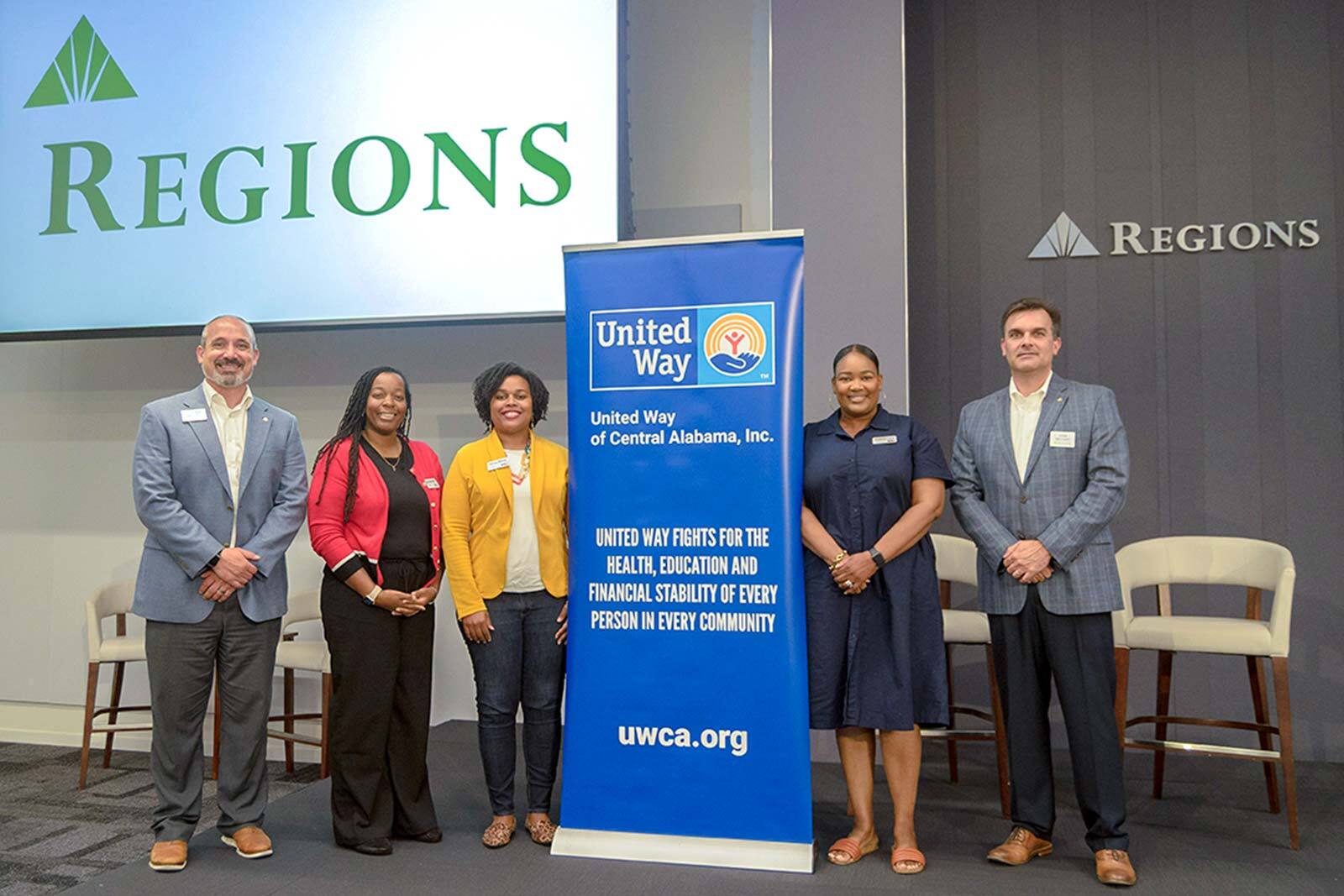 Group of Regions associates standing on either side of a United Way banner.