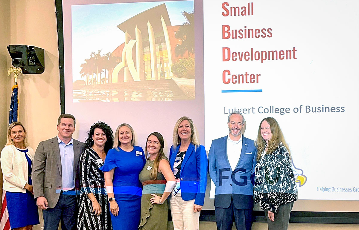 Group photo in front of Small Business Development Center presentation.