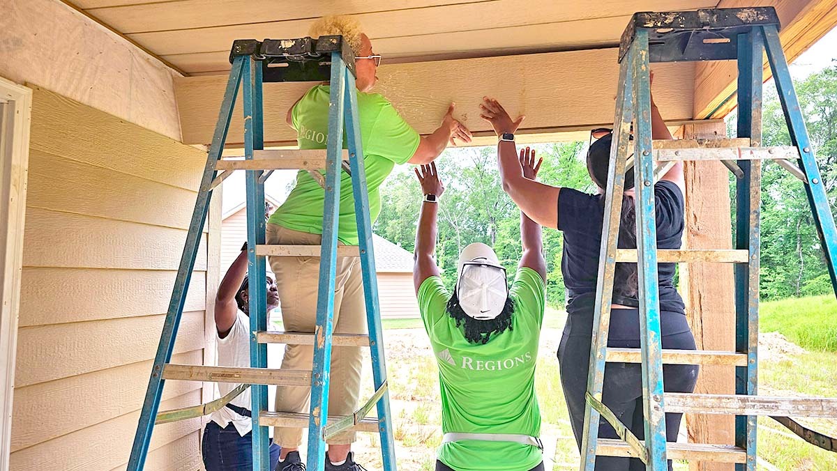 Three members of the Regions Compliance team working on the porch roof of a Habitat for Humanity build.
