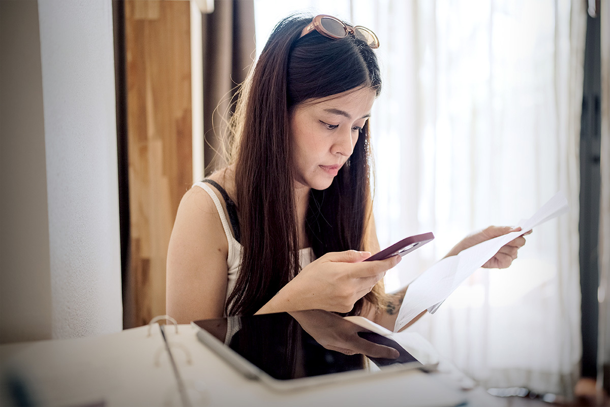 Young woman scanning a QR code from a piece of paper with her phone.
