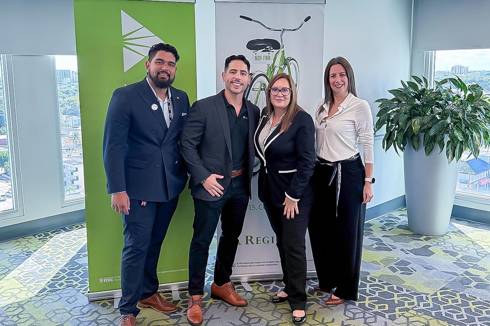 Group photo of two men and two women in front of Regions banners.