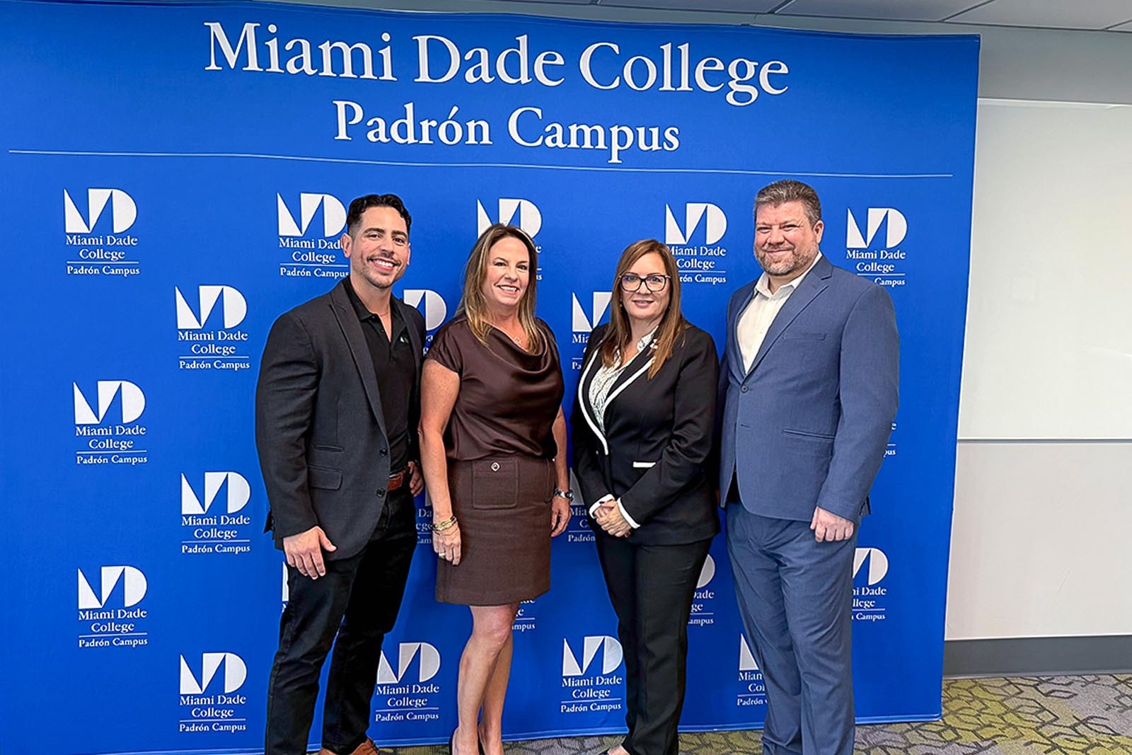 A group of four people in front of a Miami Dade College backdrop.