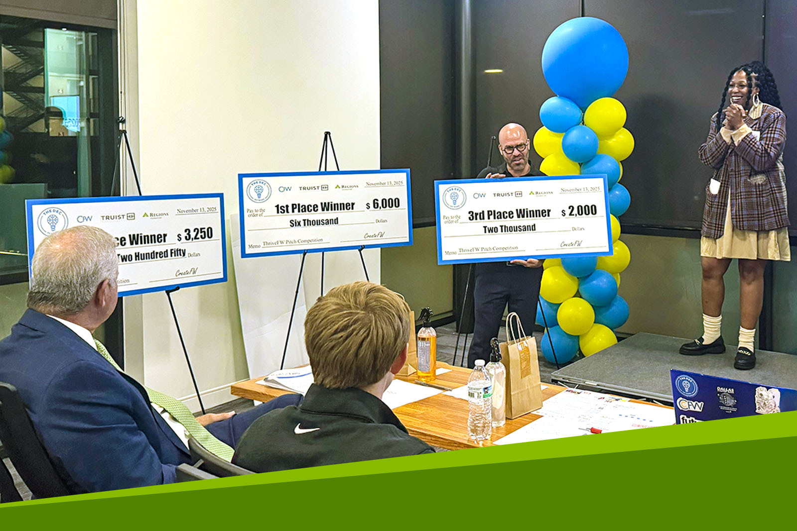 Danielle Lindsey on stage with large checks for CreateFW Thrive...