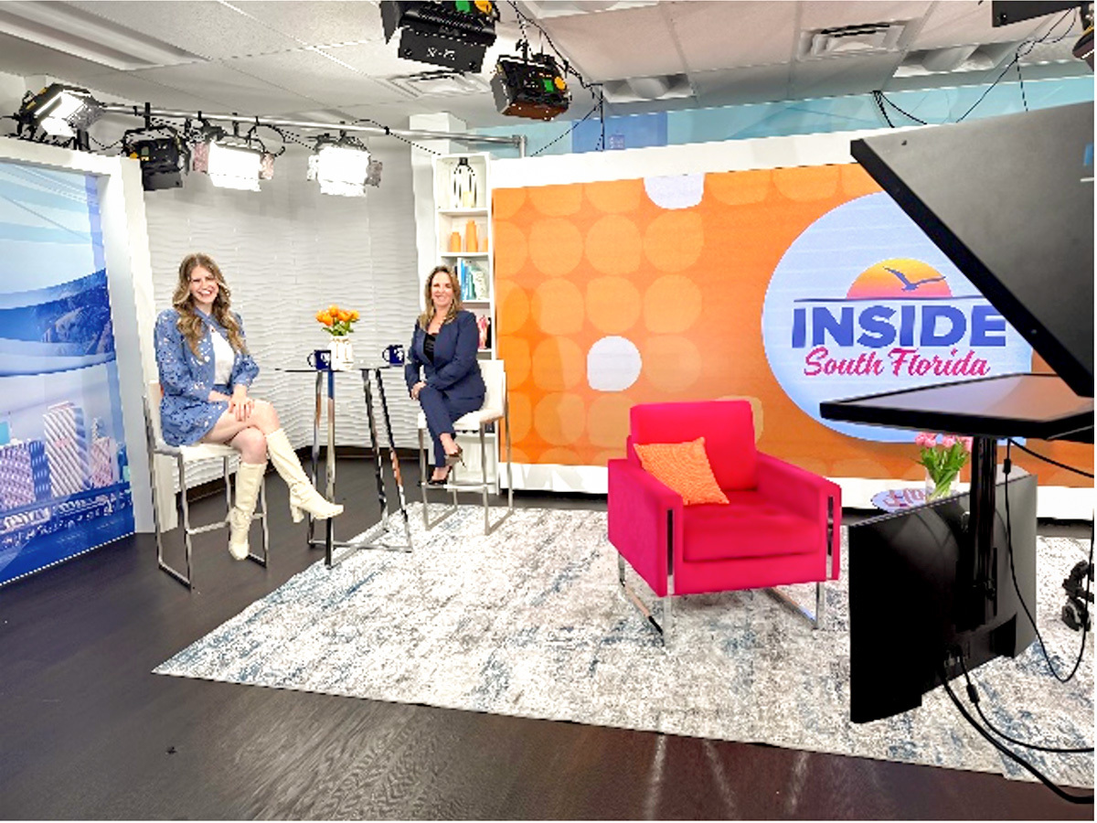 Two women seated in conversation on a news studio set. 