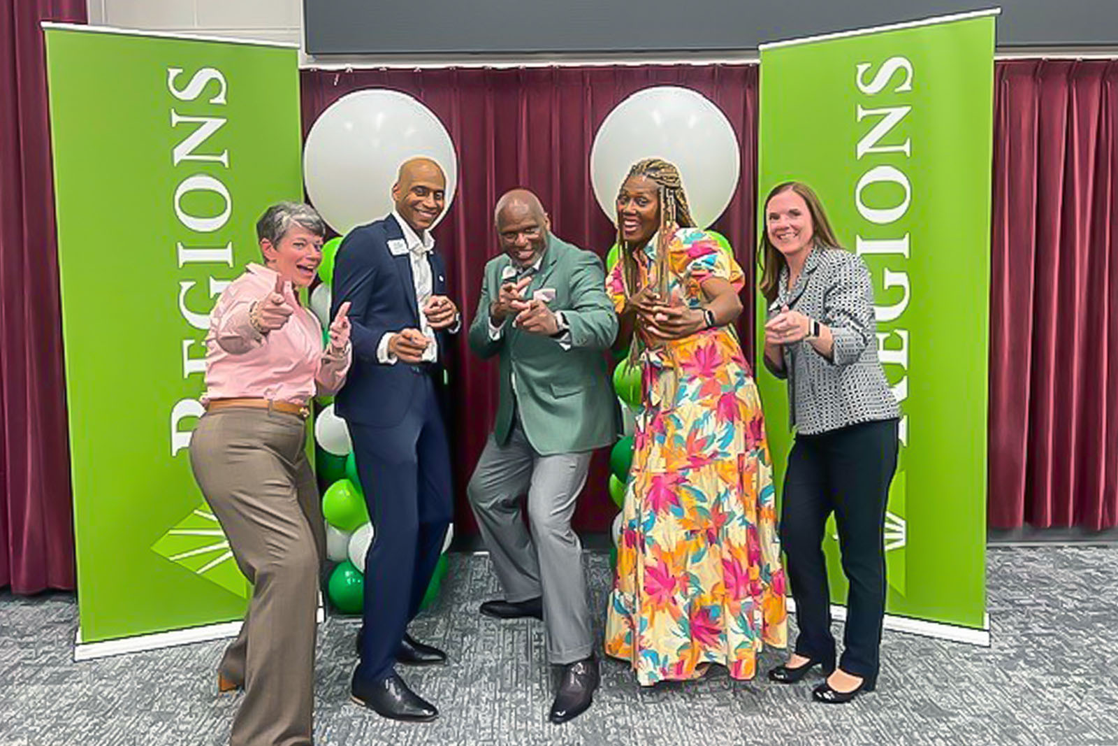 Regions associates fun posing in front of Regions banner.
