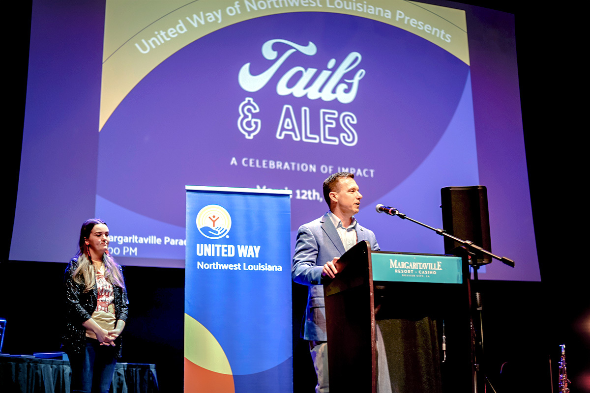Denny Moton speaking at a podium at a United Way "Tails and Ales" event. 