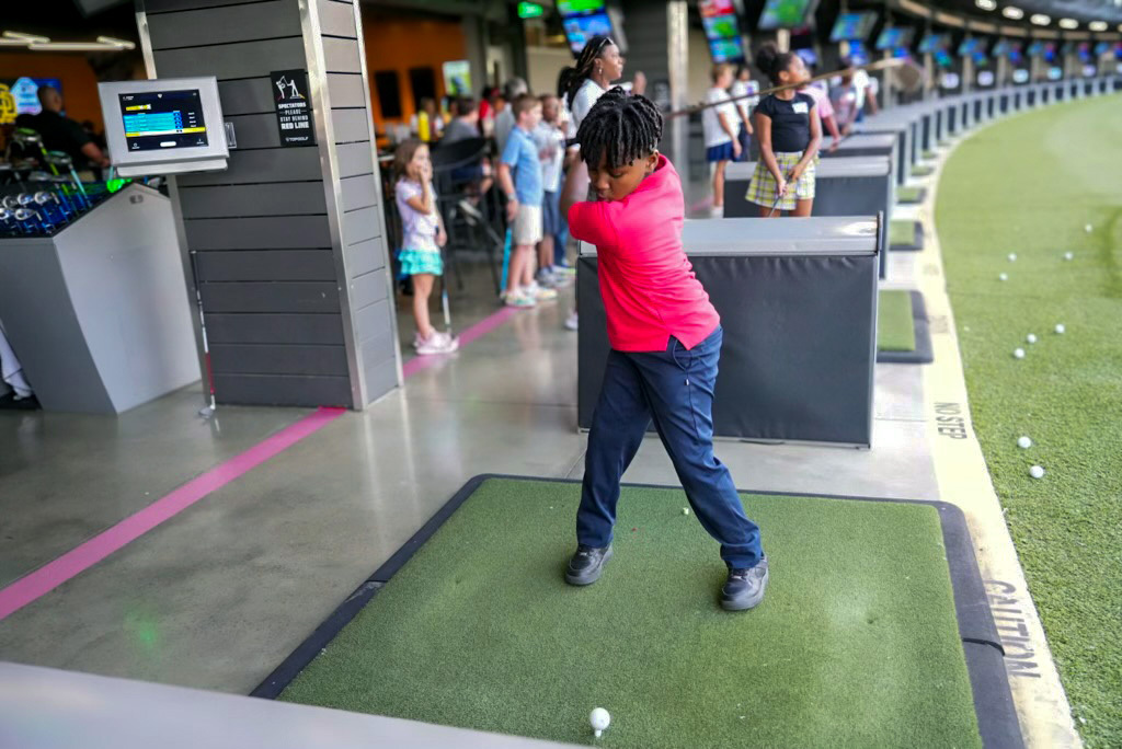Young First Tee golfer swinging golf club.