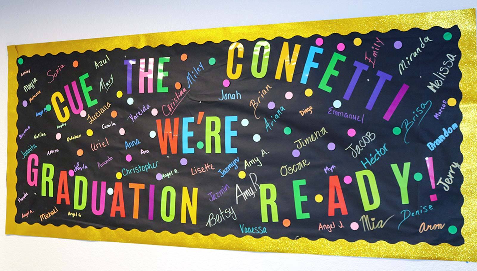 Graduation board featuring student names across the board with confetti scattered throughout.