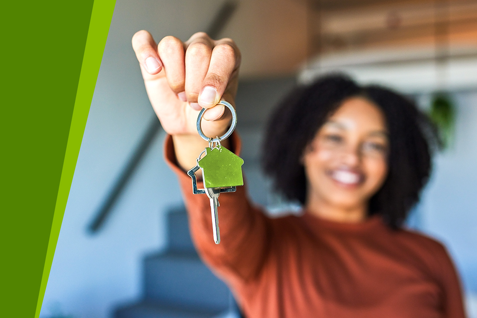 Smiling woman in background holding a key chain with green...