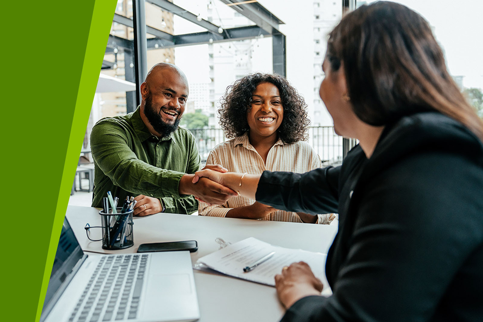 Friendly mortgage loan officer shaking hands with clients.