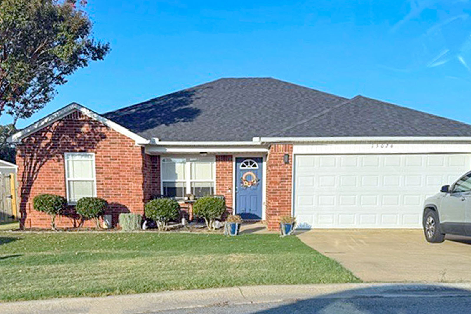 Nicole Dooley's home. A one story brick ranch with a blue door and manicured lawn.