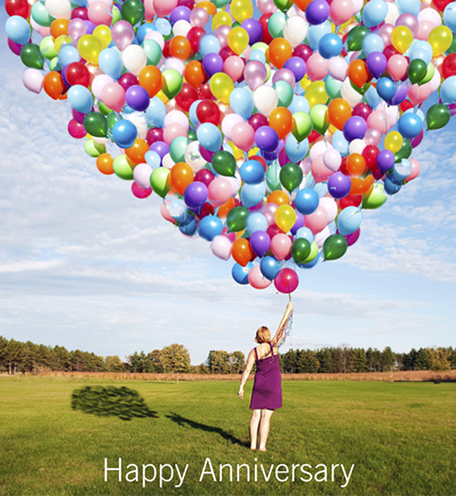Woman holding giant bouquet of balloons. Text: Happy Anniversary.