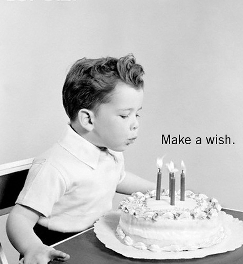 Child blowing out candles on birthday cake. Text: Make a wish.