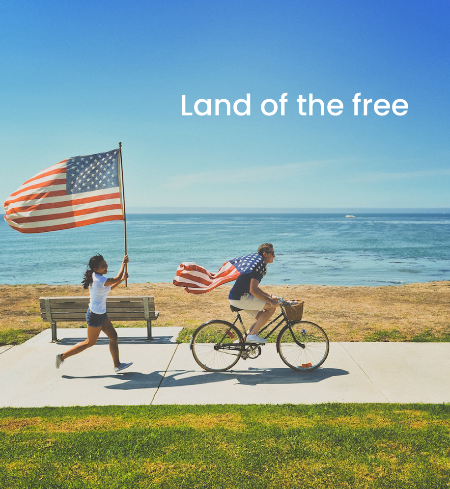 Man riding on bike with American flagged tied around his shoulder. A woman is running behind him holding an American flag above her head. Text: Land of the free.